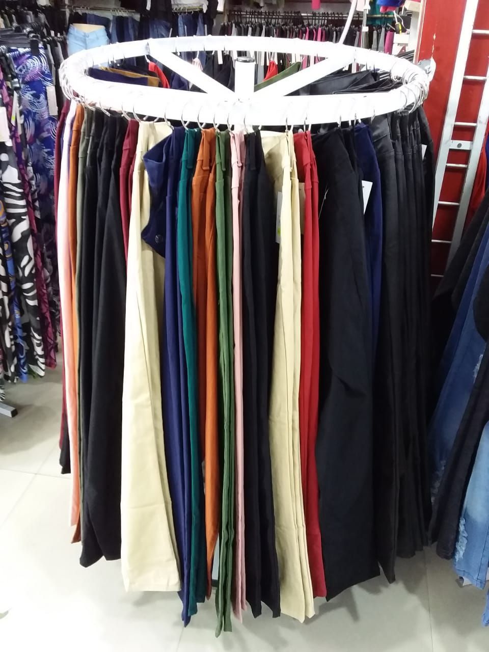 Un perchero circular que muestra pantalones de varios colores en una tienda.