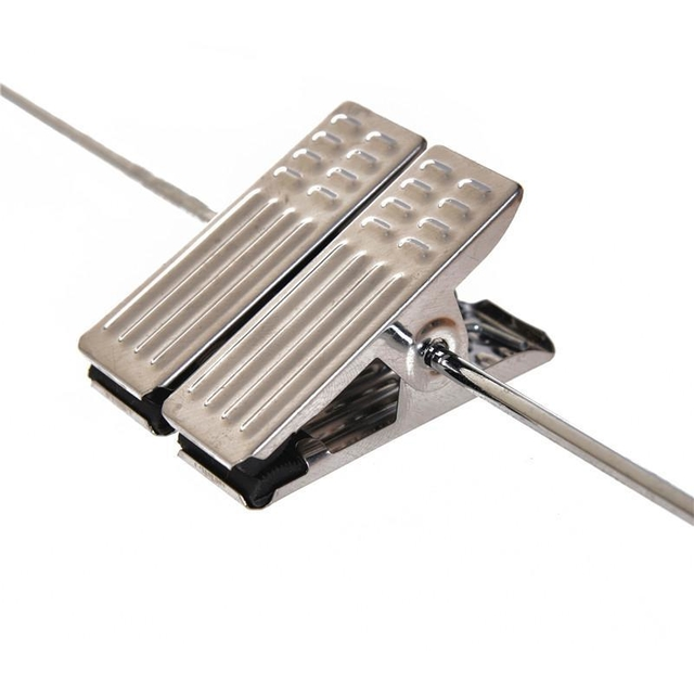 Pinza de ropa de metal sobre un alambre fino, sujetándola en su lugar; toma de primer plano.
