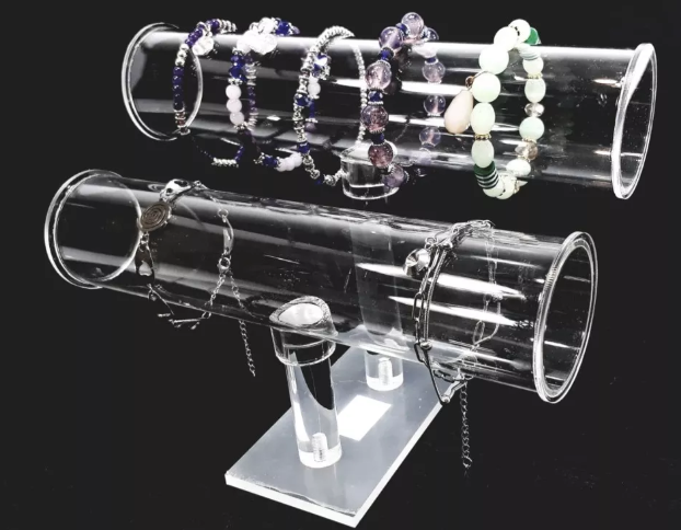 Expositor de joyas de acrílico transparente con pulseras, fondo negro.