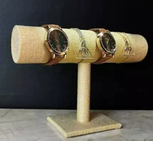 Un expositor de joyas con una barra cilíndrica de color tostado que sostiene dos relojes y una pulsera