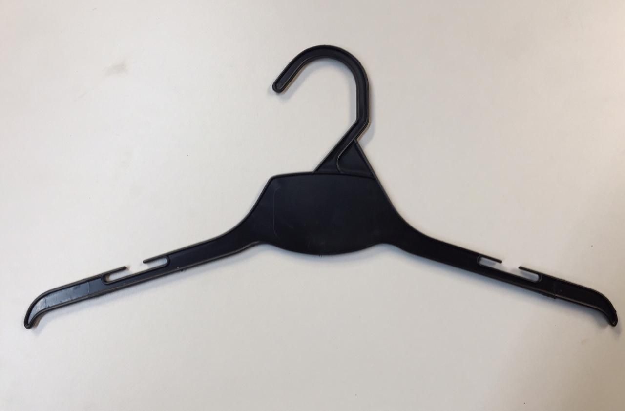 Percha de ropa de plástico negra sobre una superficie blanca.