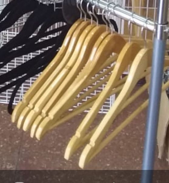 Perchas de ropa de madera y color negro colgadas en un estante de metal.