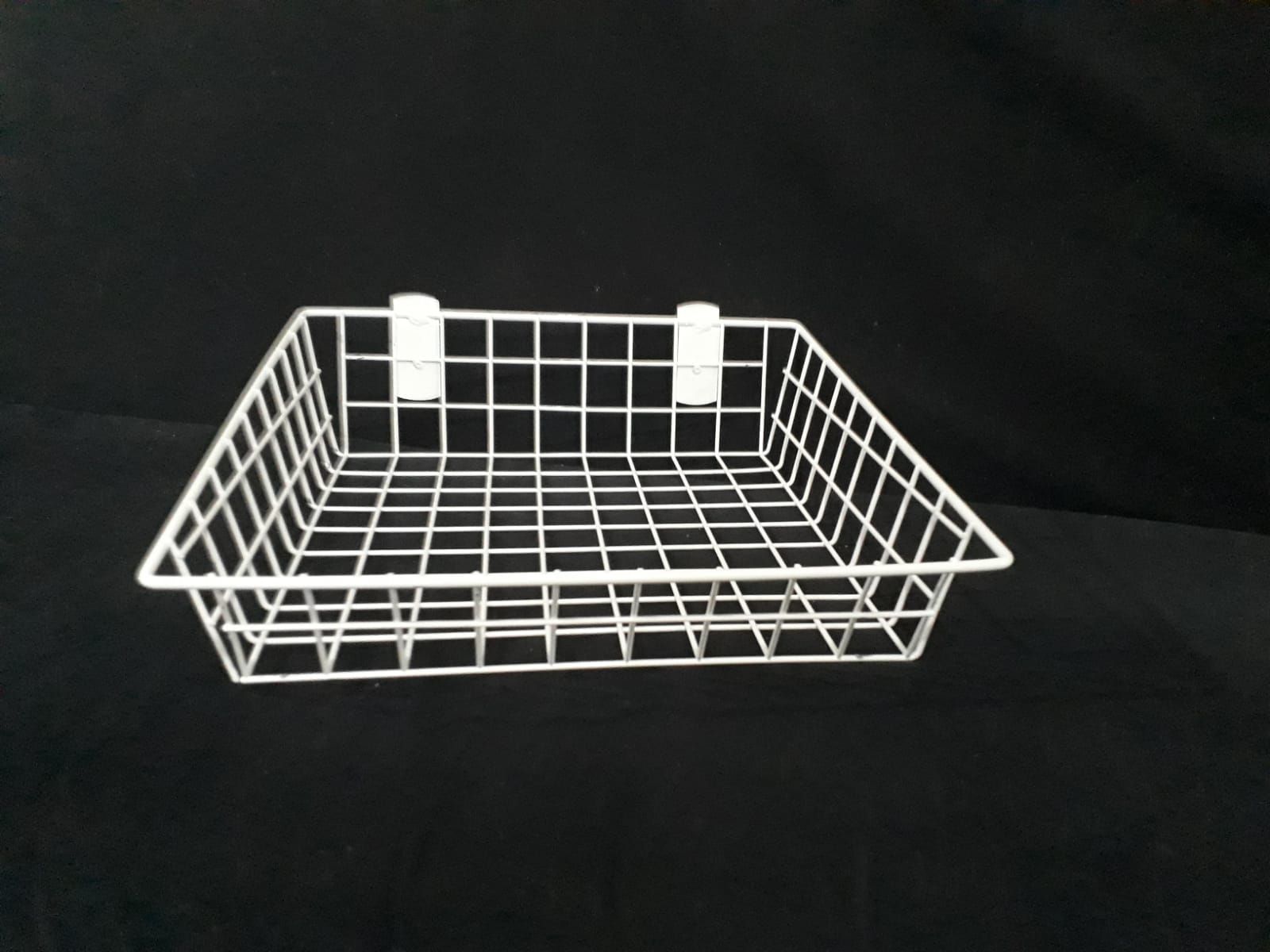 Cesta de alambre blanca con dos clips blancos, sobre fondo negro.