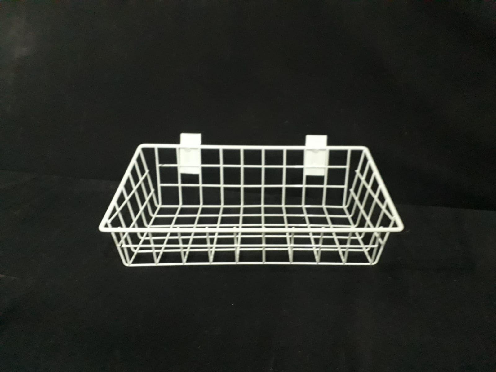 Cesta de alambre blanca con dos ganchos adjuntos sobre un fondo negro.