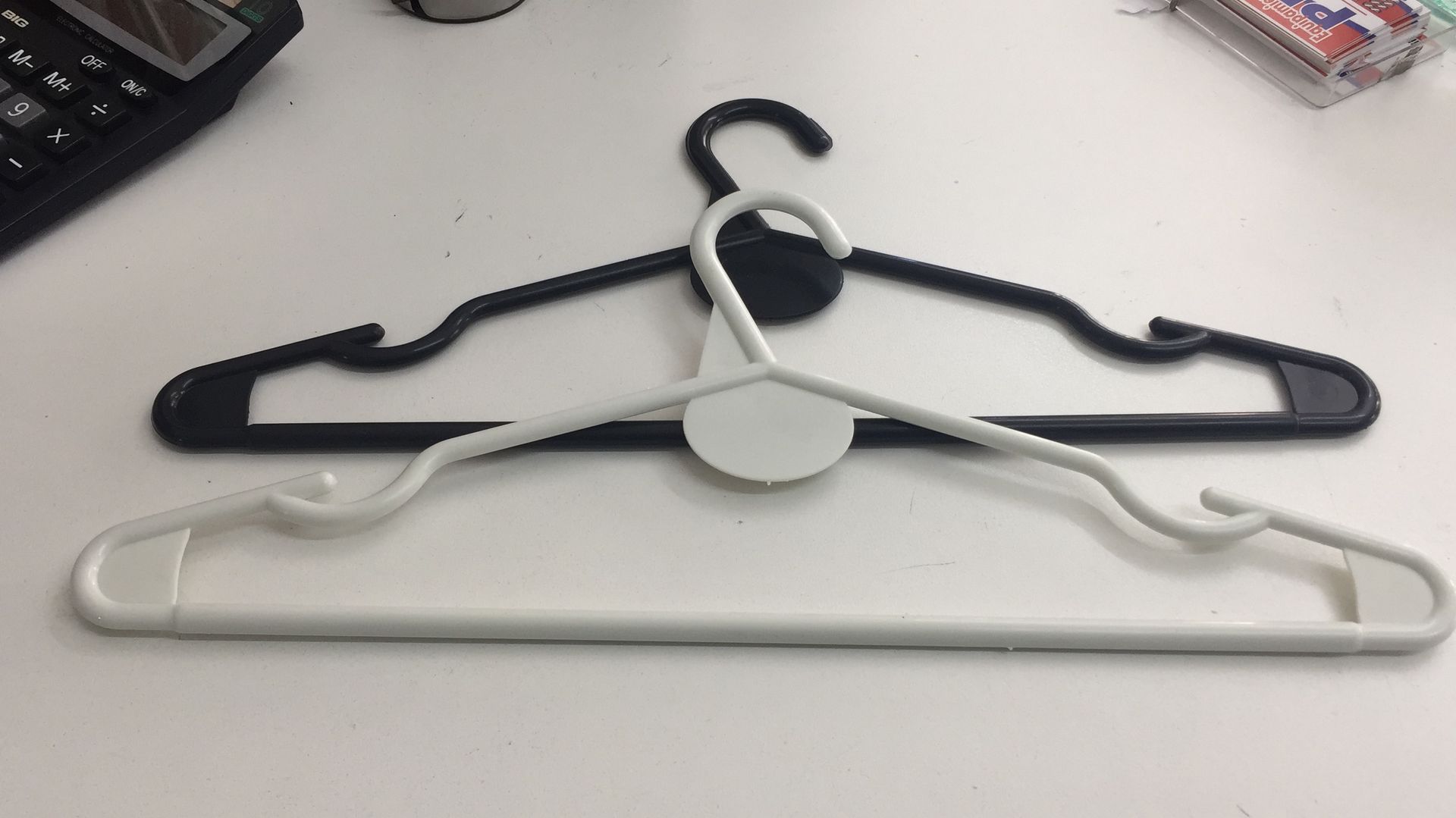 Perchas de ropa de plástico en blanco y negro sobre una superficie blanca.