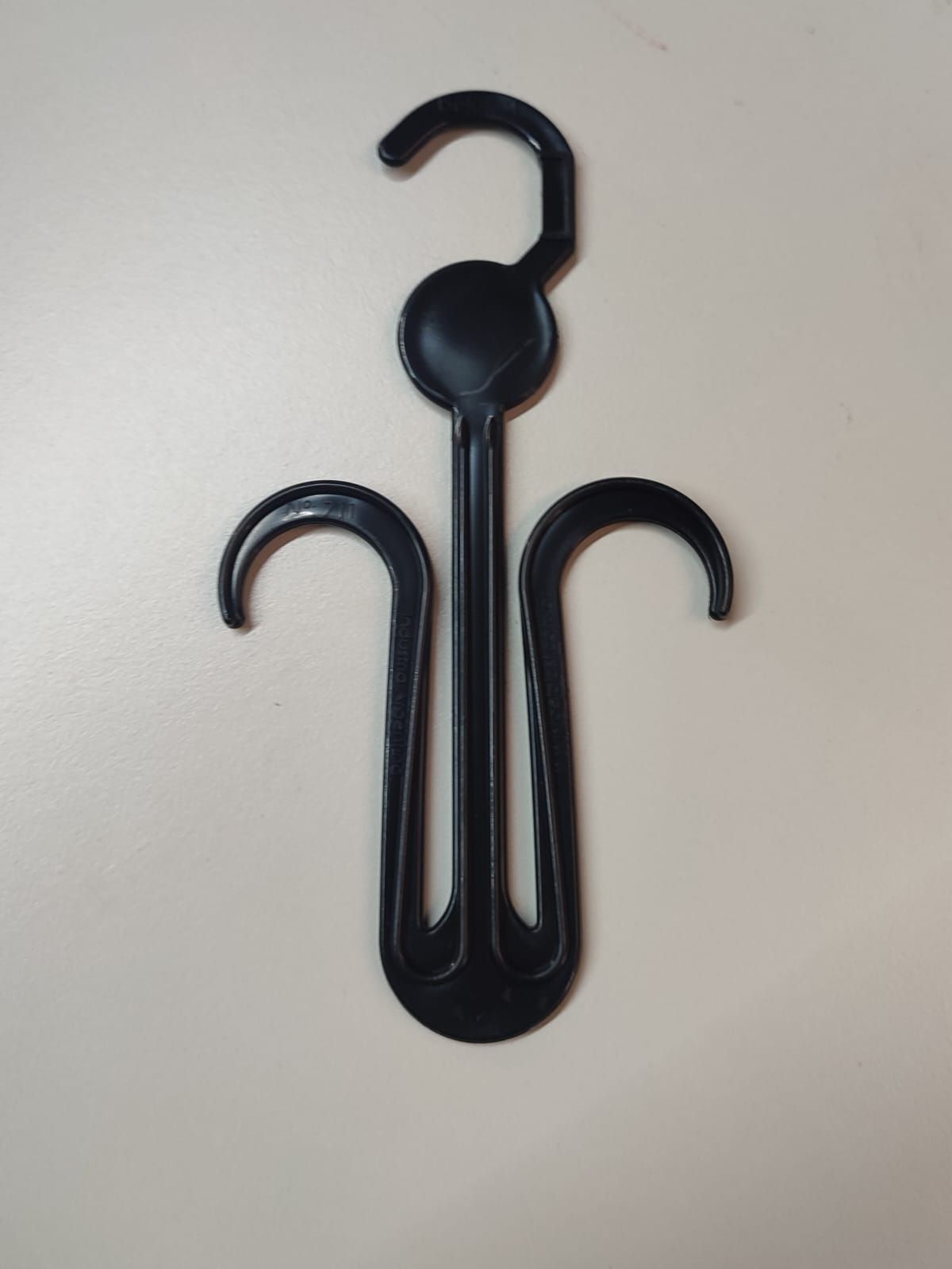 Percha para zapatos de plástico negro con gancho y dos soportes curvados para zapatos.