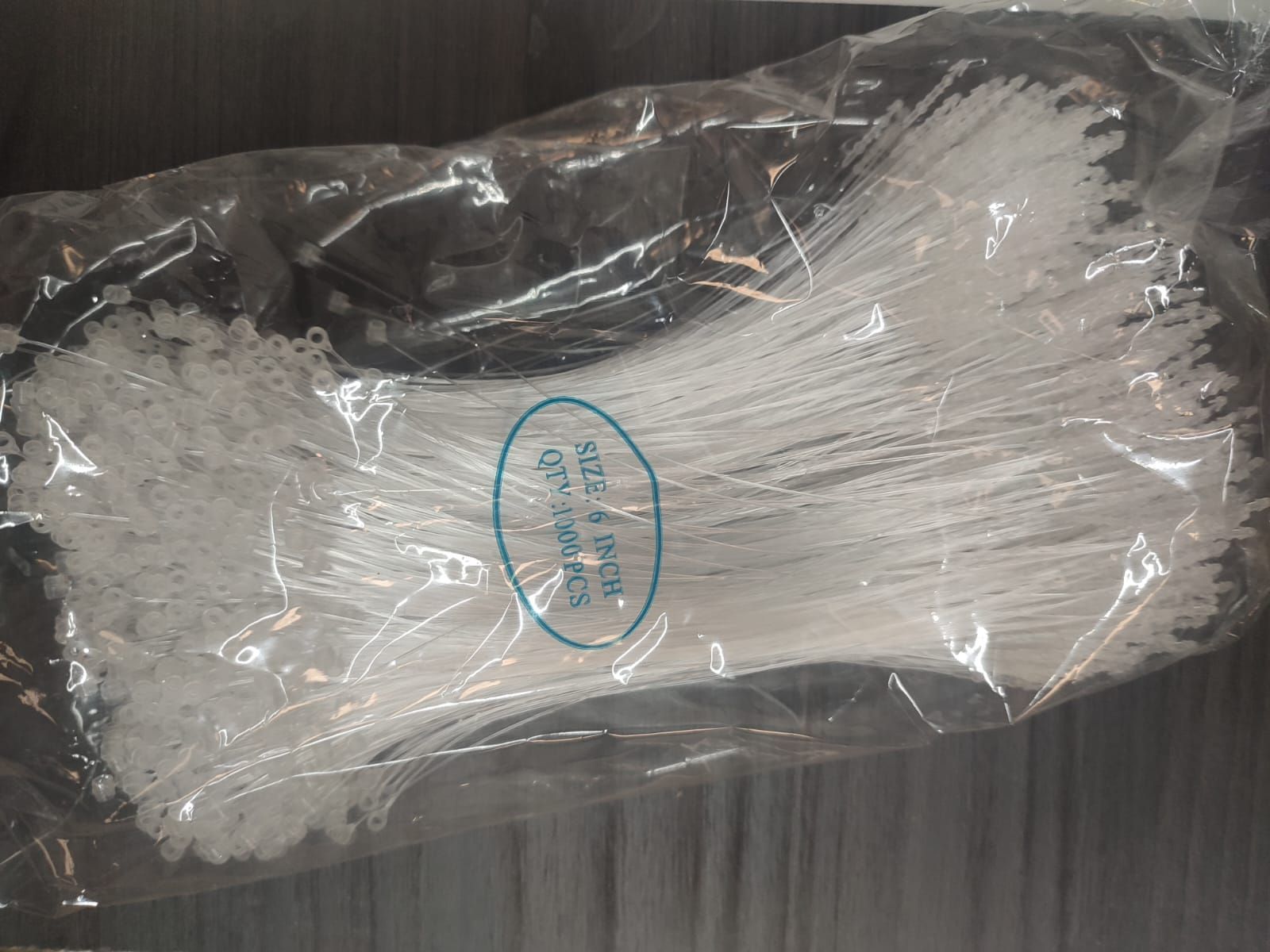 Paquete de sujetadores de etiquetas de plástico blanco en una bolsa de plástico transparente.