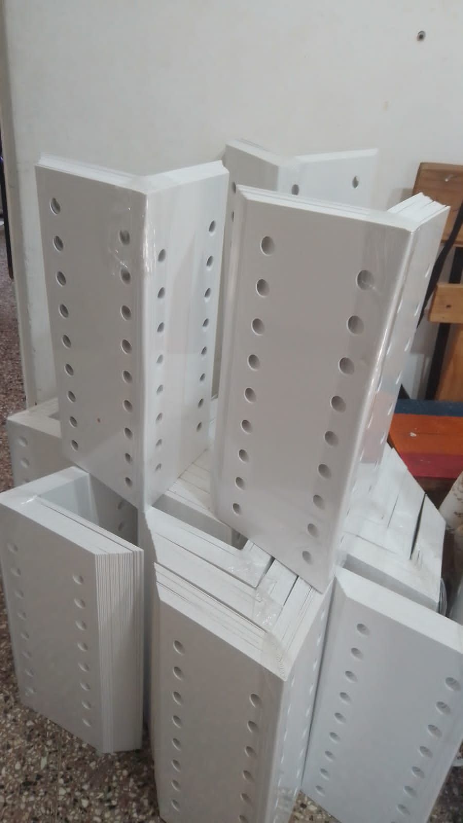 Pilas de objetos rectangulares blancos con agujeros espaciados uniformemente, envueltos en plástico transparente.