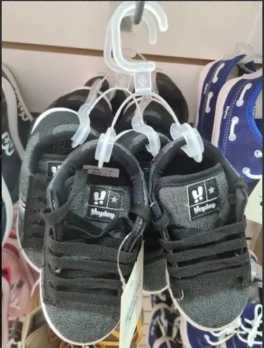 Pequeños zapatos de bebé negros colgados en exhibición en una tienda.