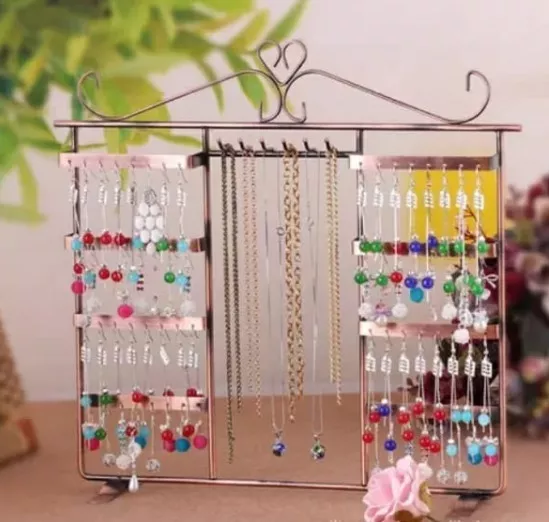 Organizador de joyas de metal de bronce que contiene varios aretes y collares.