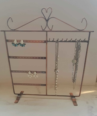 Organizador de joyas de metal en tono cobre con aretes y collares exhibidos.