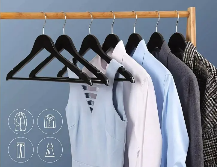 Ropa colgada en perchas de madera negras sobre un estante.