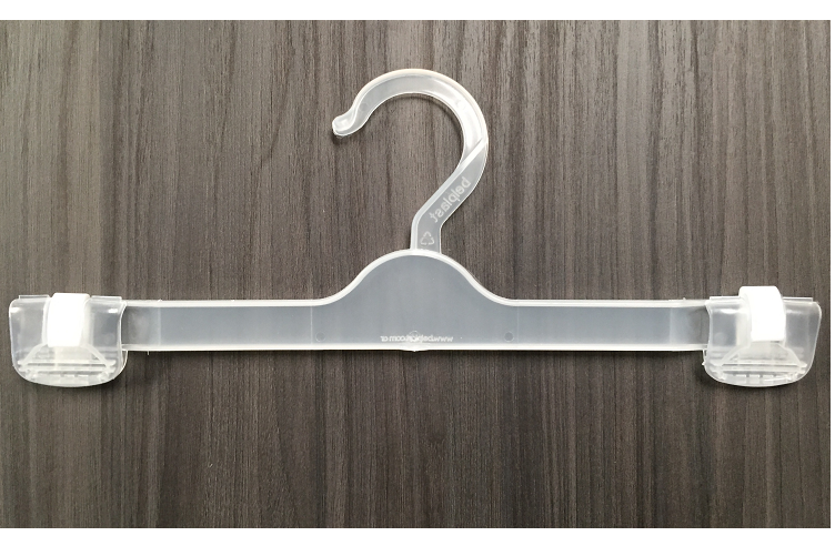 Percha de ropa de plástico transparente con pinzas sobre un fondo de veta de madera gris.