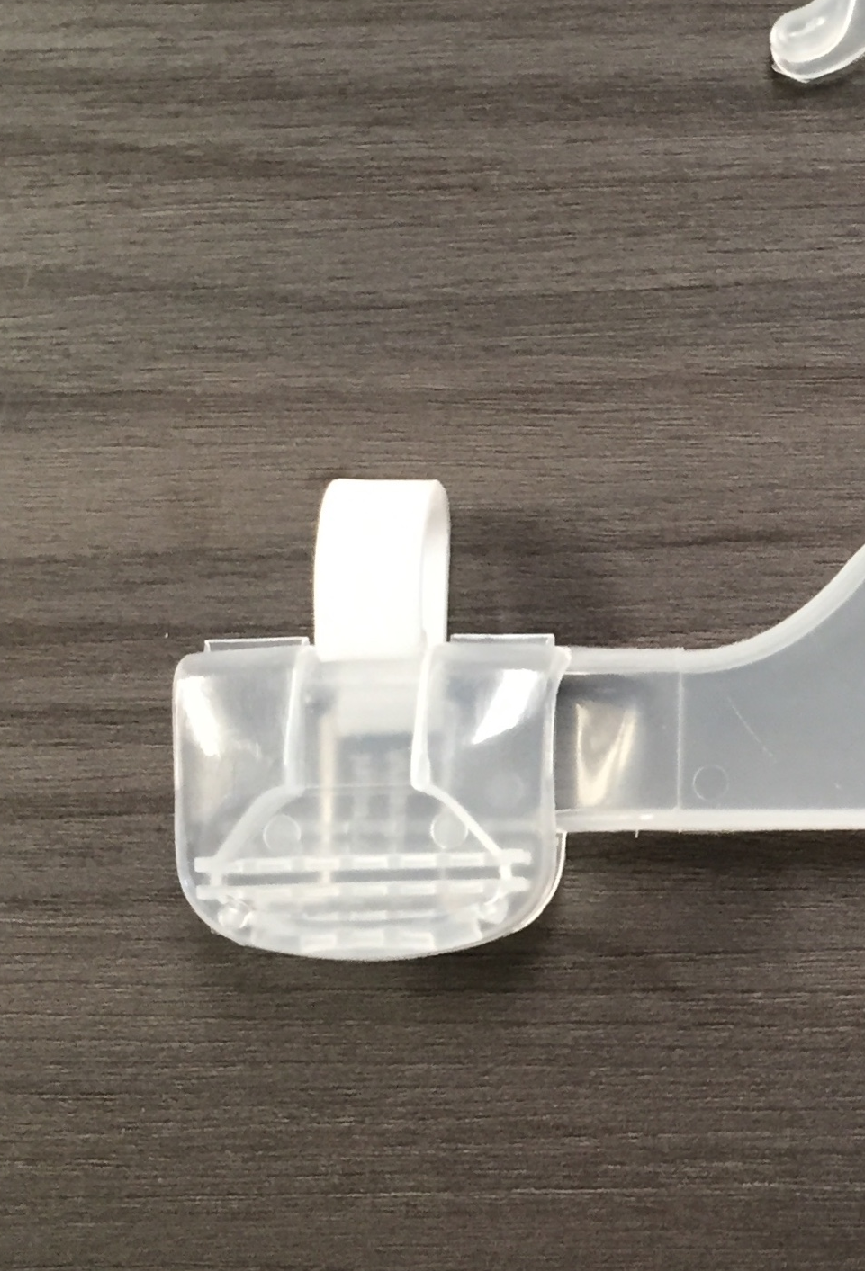 Primer plano de un clip de suspensión de plástico transparente con una pestaña blanca