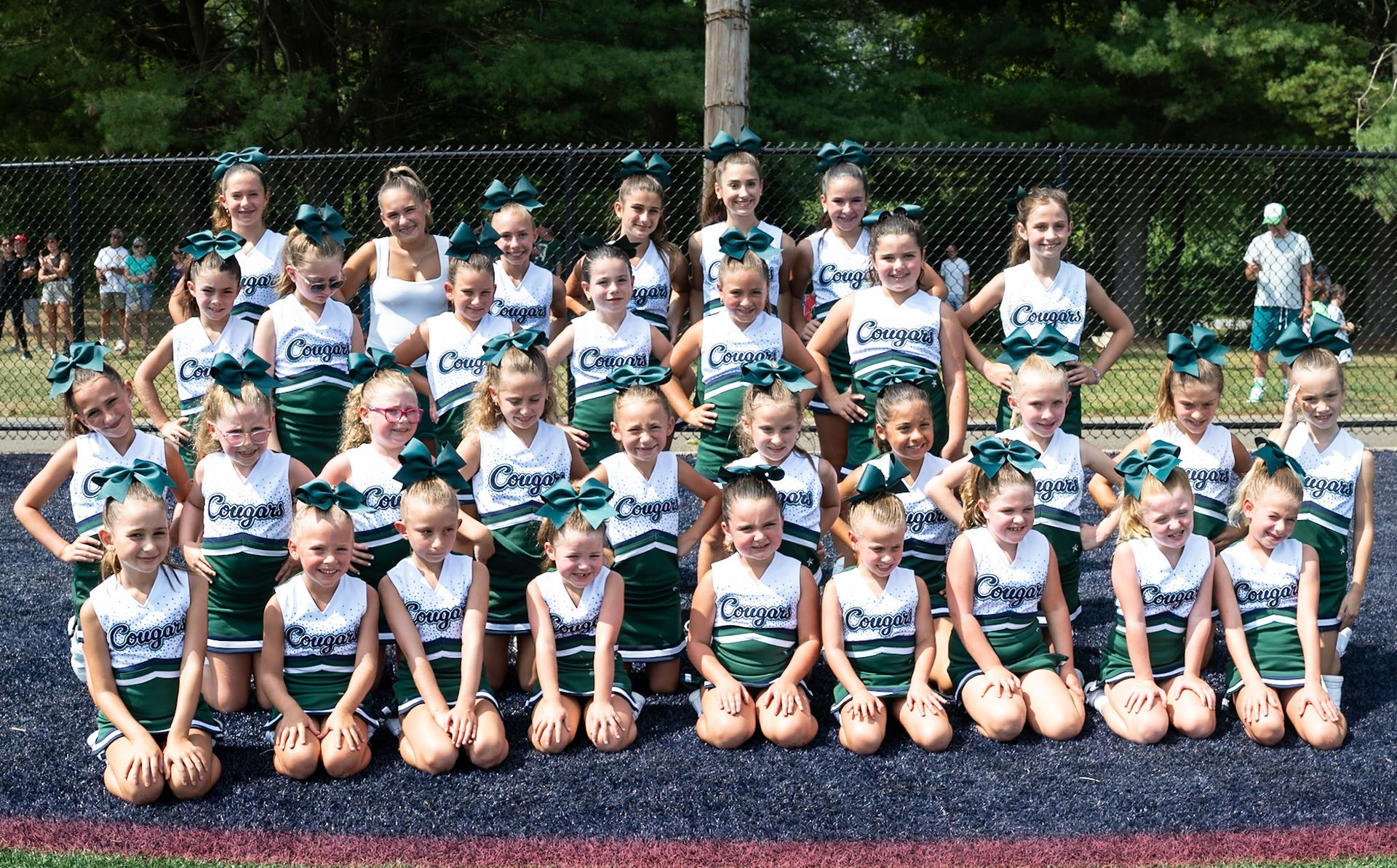 Cheerleader in red uniform performs a backbend on a green and red football field.