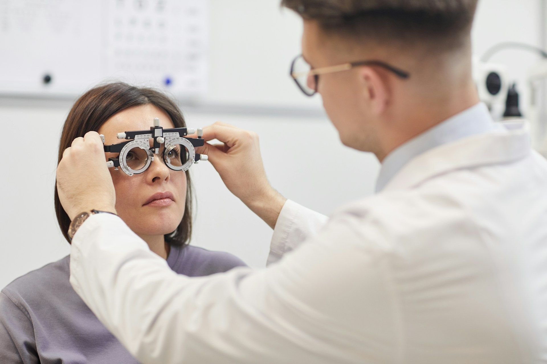 Eye exam with optometrist adjusting phoropter on a patient in a clinic