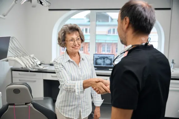Two people shaking hands in a bright office reception area