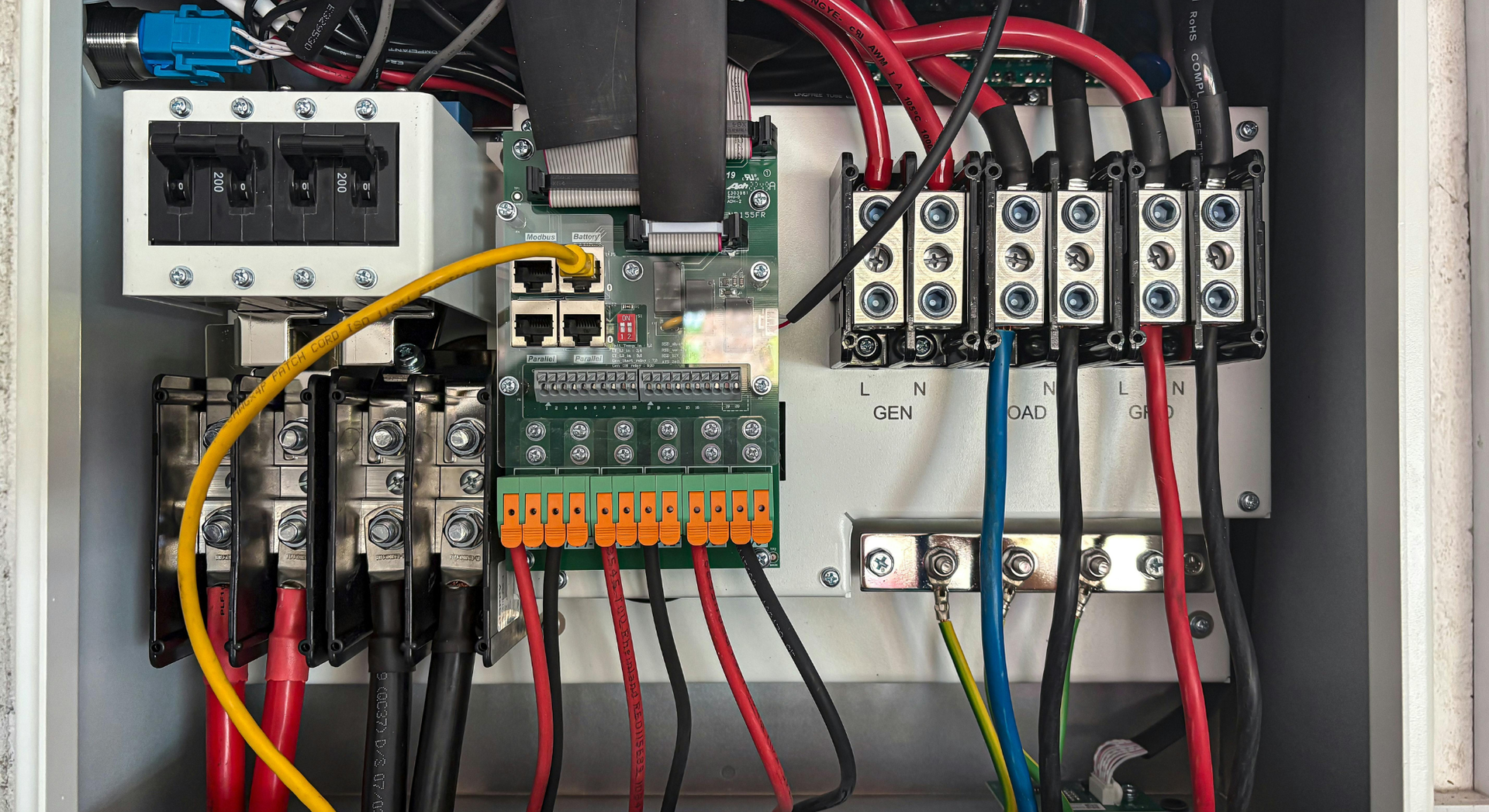Electrical panel with various wires, connectors, and circuit breakers in a metal box.