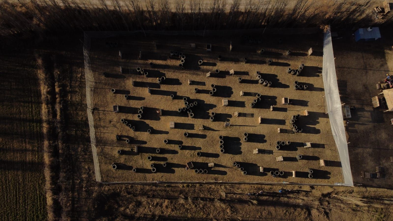 Vista aérea de un campo de paintball con numerosos bunkers repartidos por el suelo, rodeados de hierba alta.