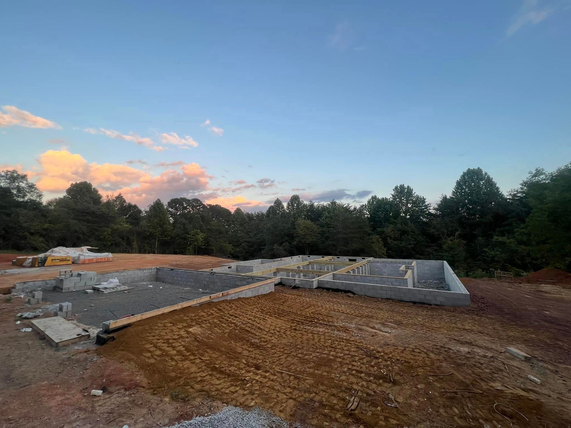 A construction site with a lot of dirt and trees in the background.
