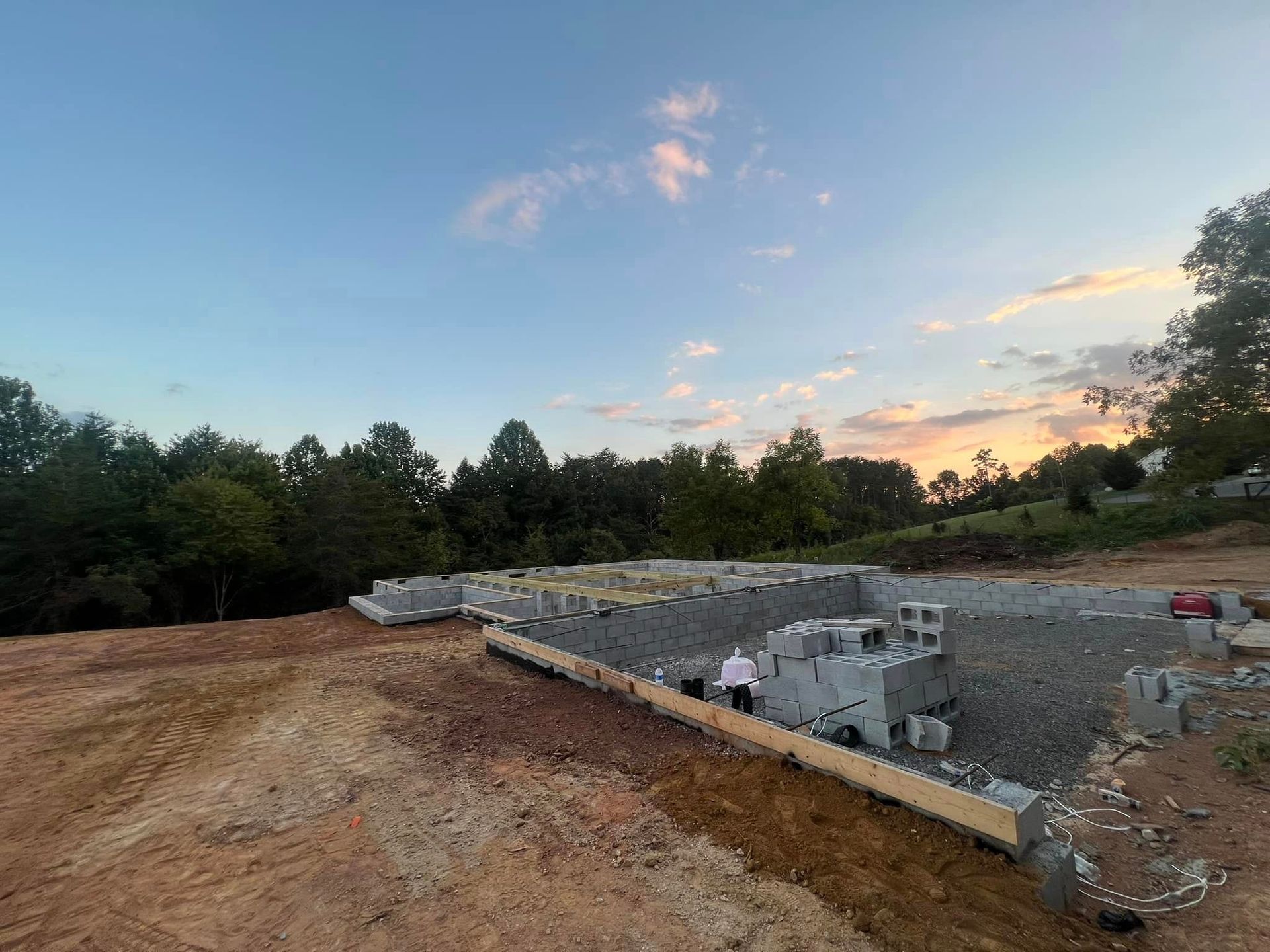 A construction site with a lot of dirt and trees in the background.