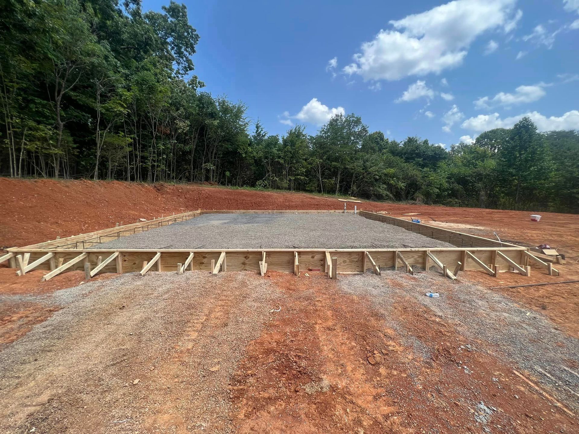 A construction site with a lot of dirt and trees in the background.