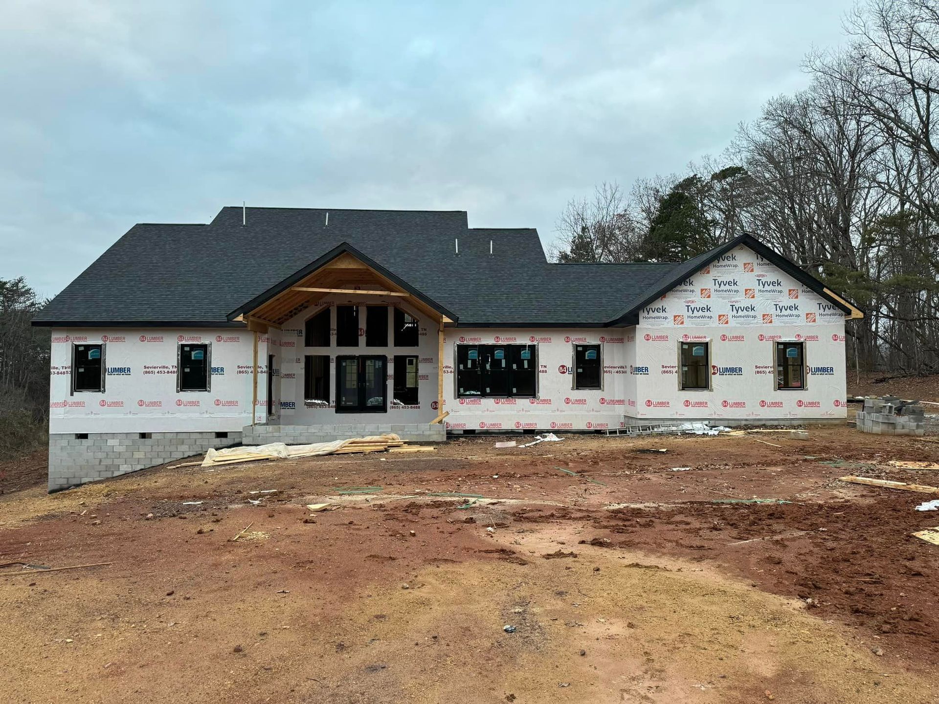 A large house is being built in the middle of a dirt field.