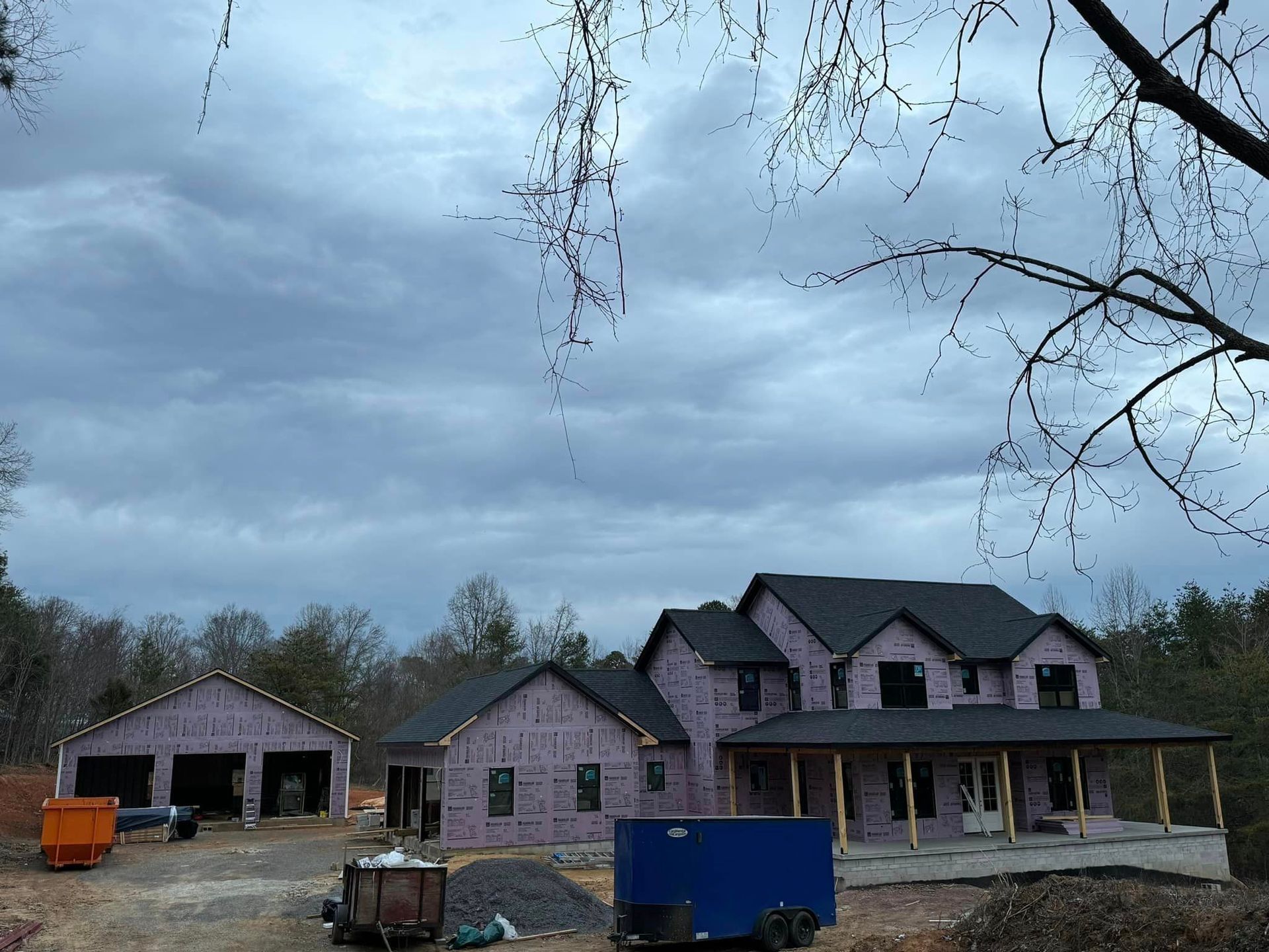 A large house under construction with a blue trailer in front of it
