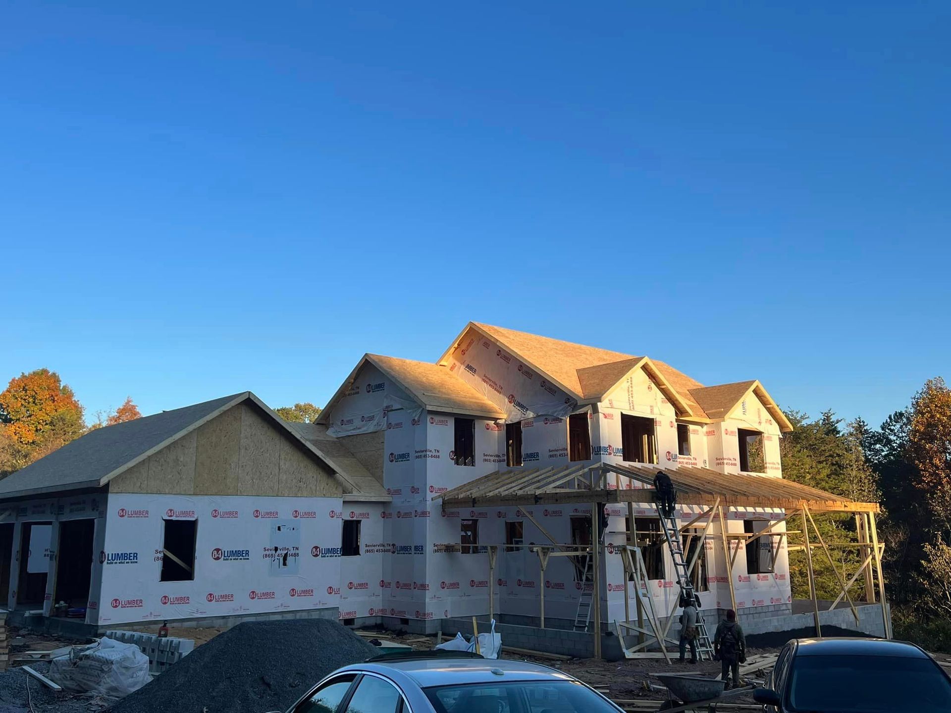 A large house is being built with a car parked in front of it.