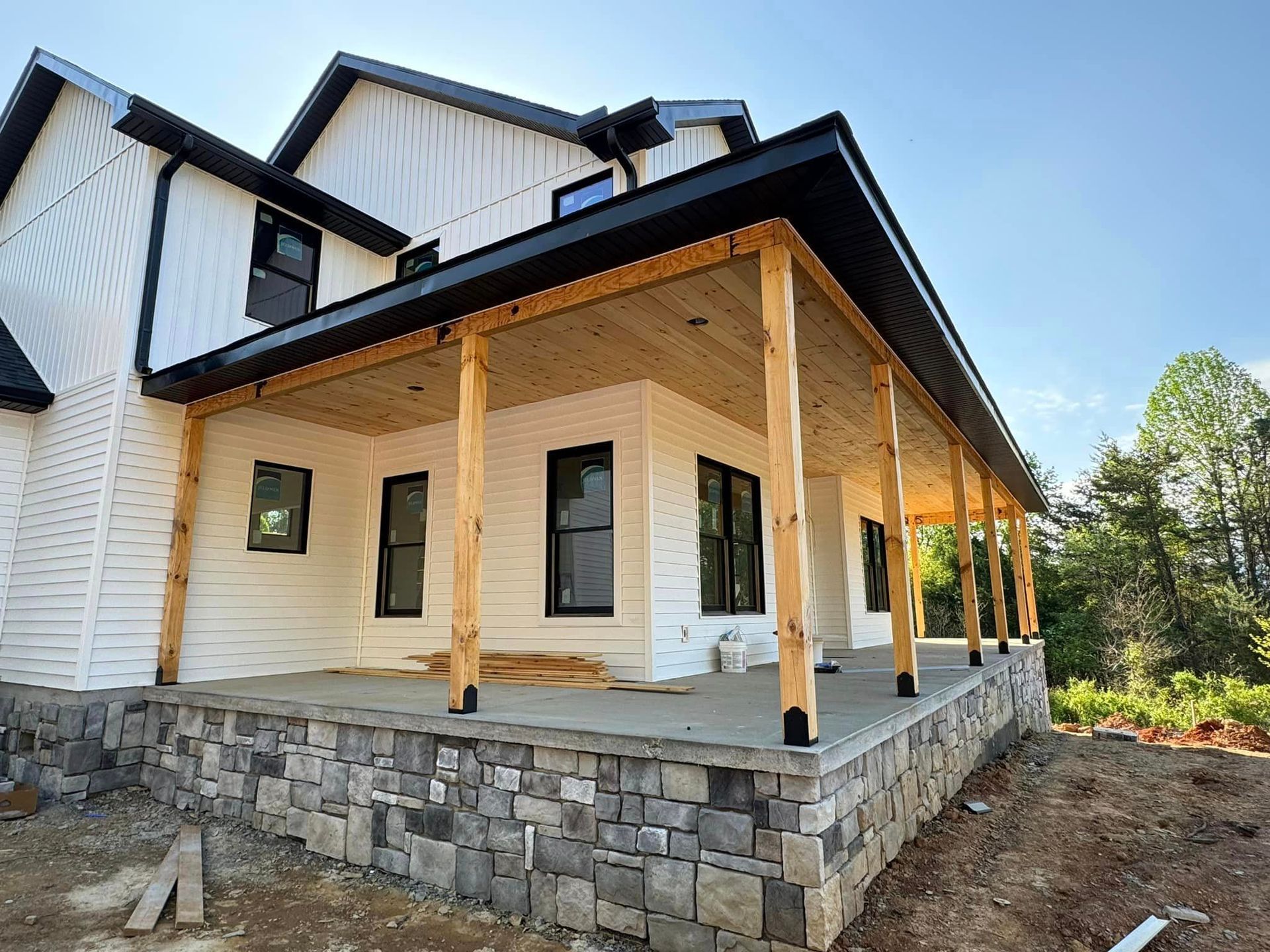 A white house with a large porch and a stone wall.