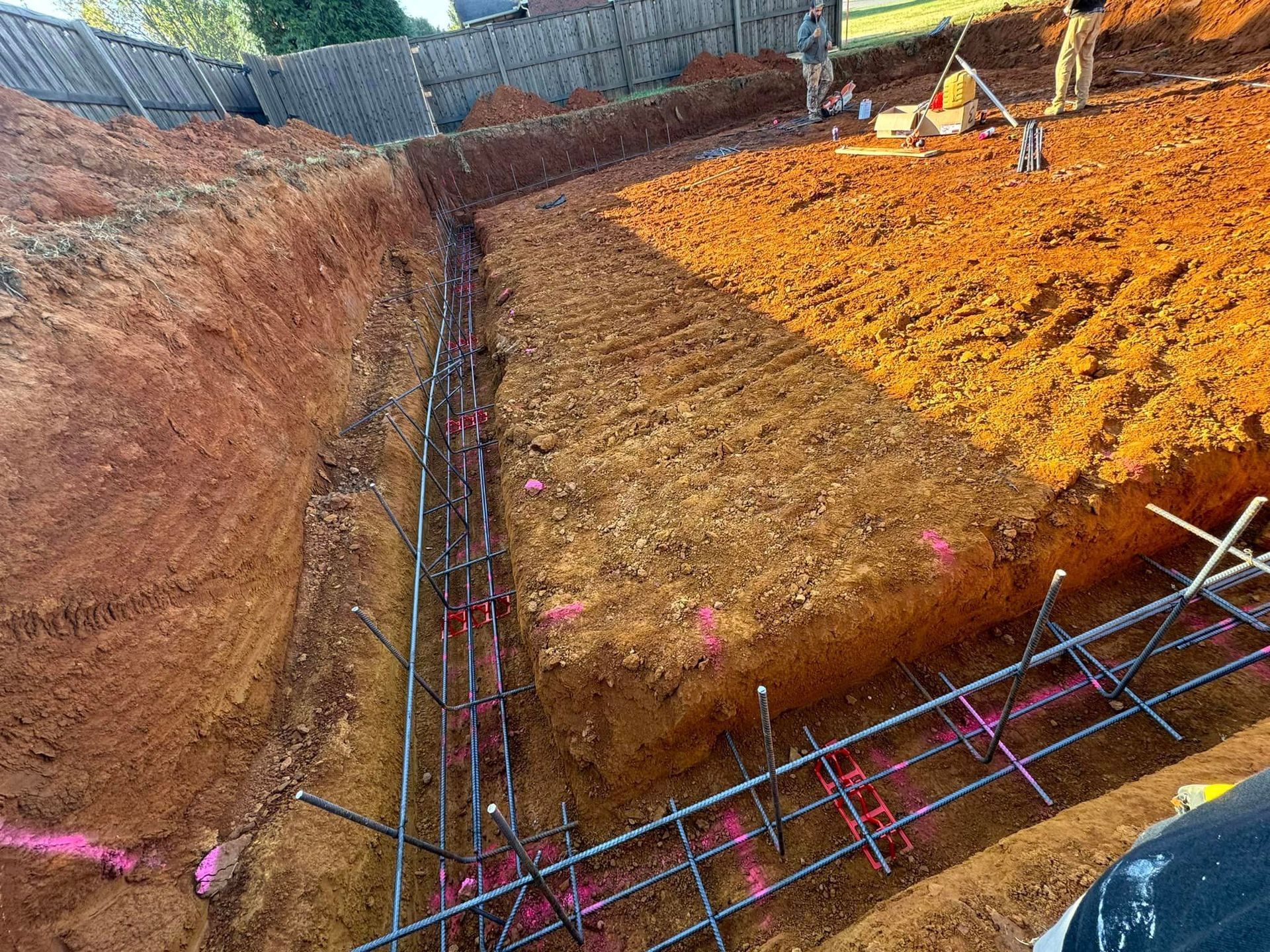 A construction site with a lot of dirt and a fence in the background.