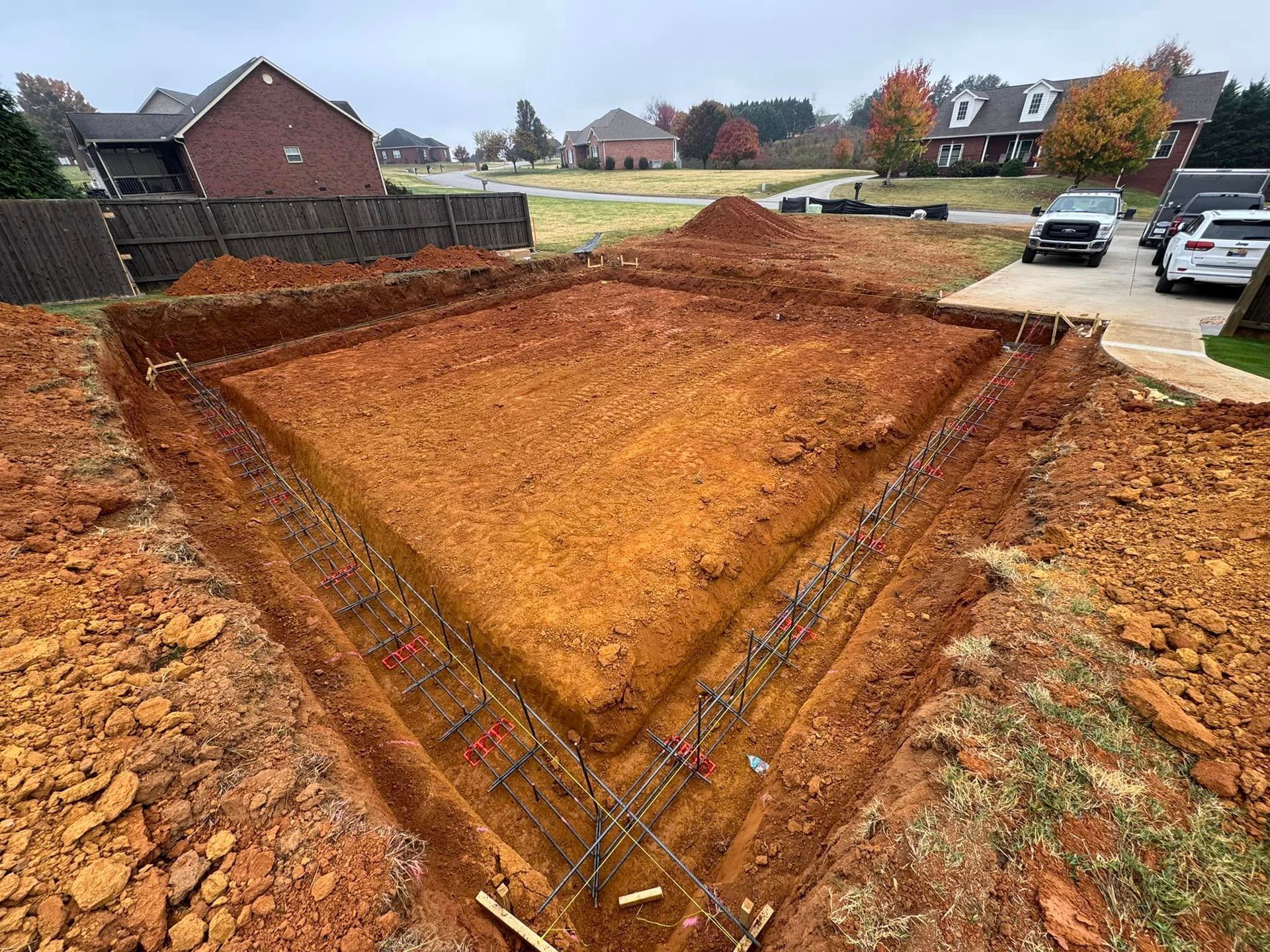 A large pile of dirt is sitting in the middle of a driveway next to a house.