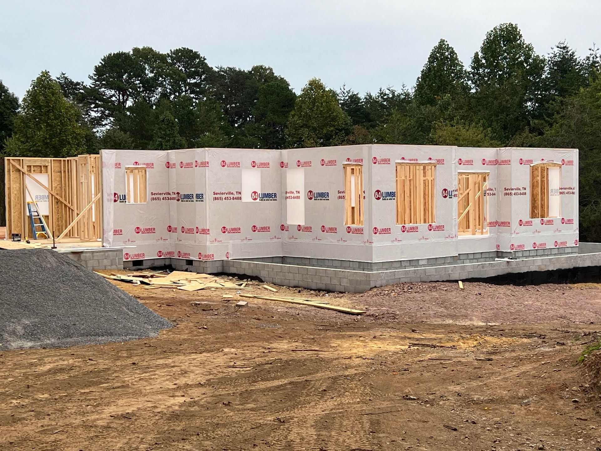 A house is being built in a field with trees in the background.