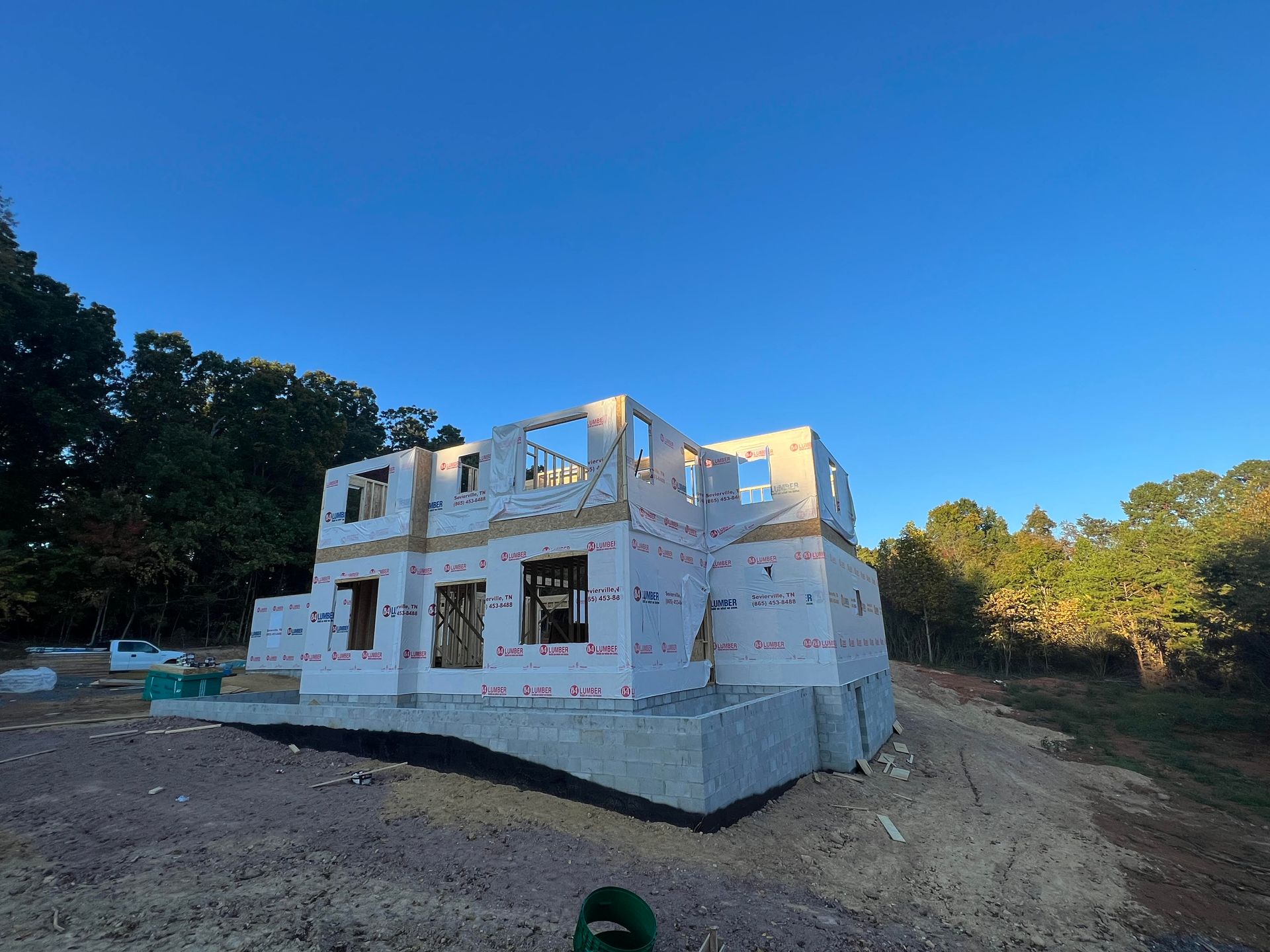 A large white house is being built in the middle of a dirt field.