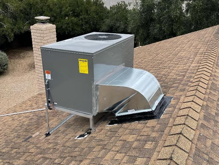 A large air conditioner is sitting on top of a brick roof.
