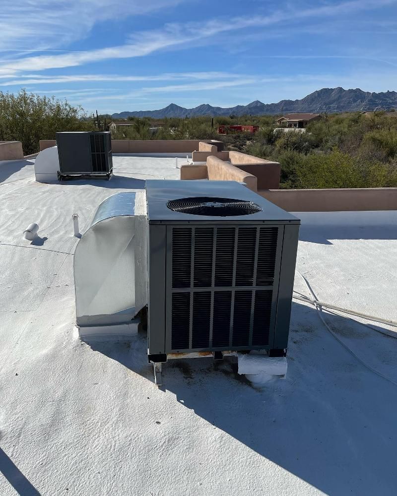 A large air conditioner is sitting on top of a white roof.