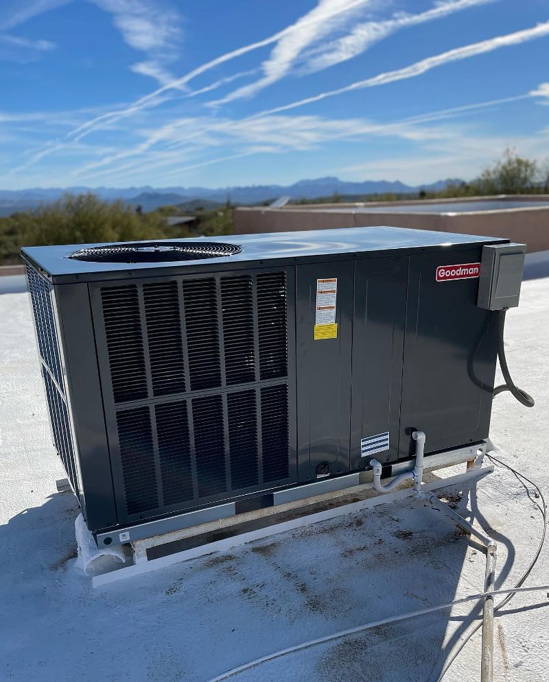 A black air conditioner is sitting on top of a white roof.