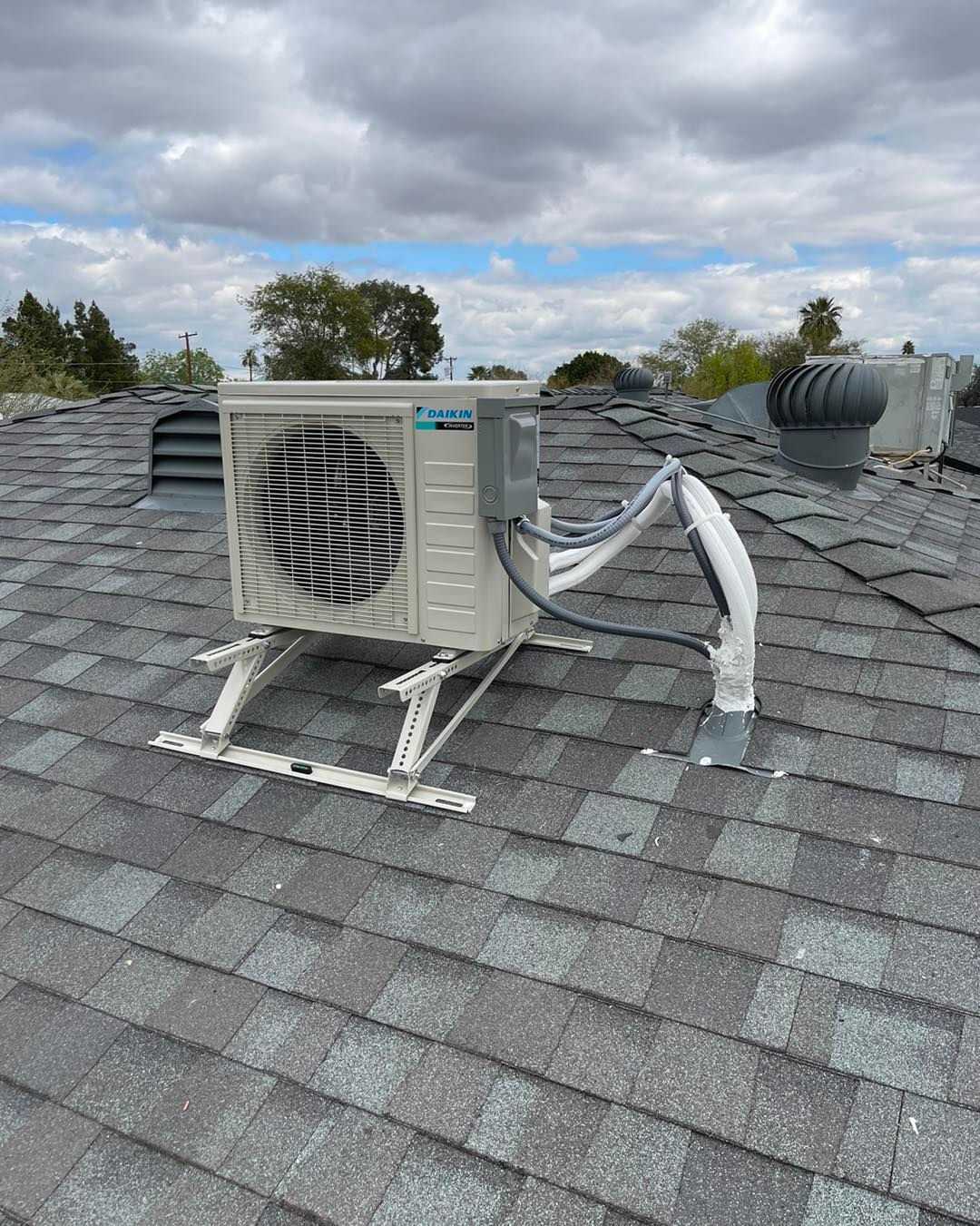 A white air conditioner is sitting on top of a roof.