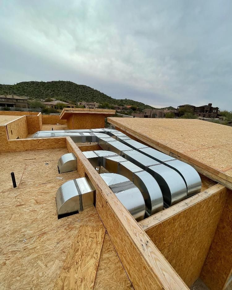 A roof with a lot of ducts on it and a mountain in the background.