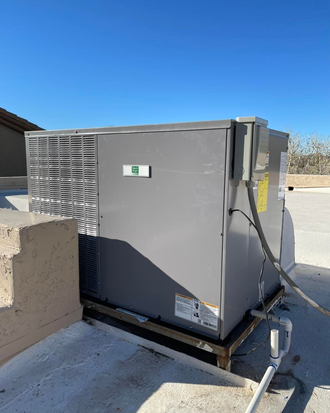 A large air conditioner is sitting on top of a concrete roof.