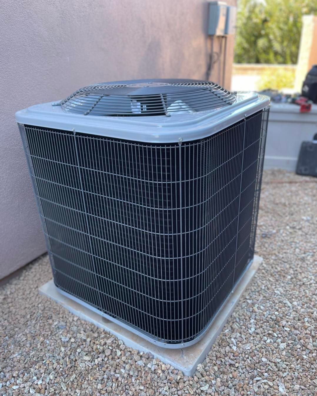 A large air conditioner is sitting on top of a pile of gravel.