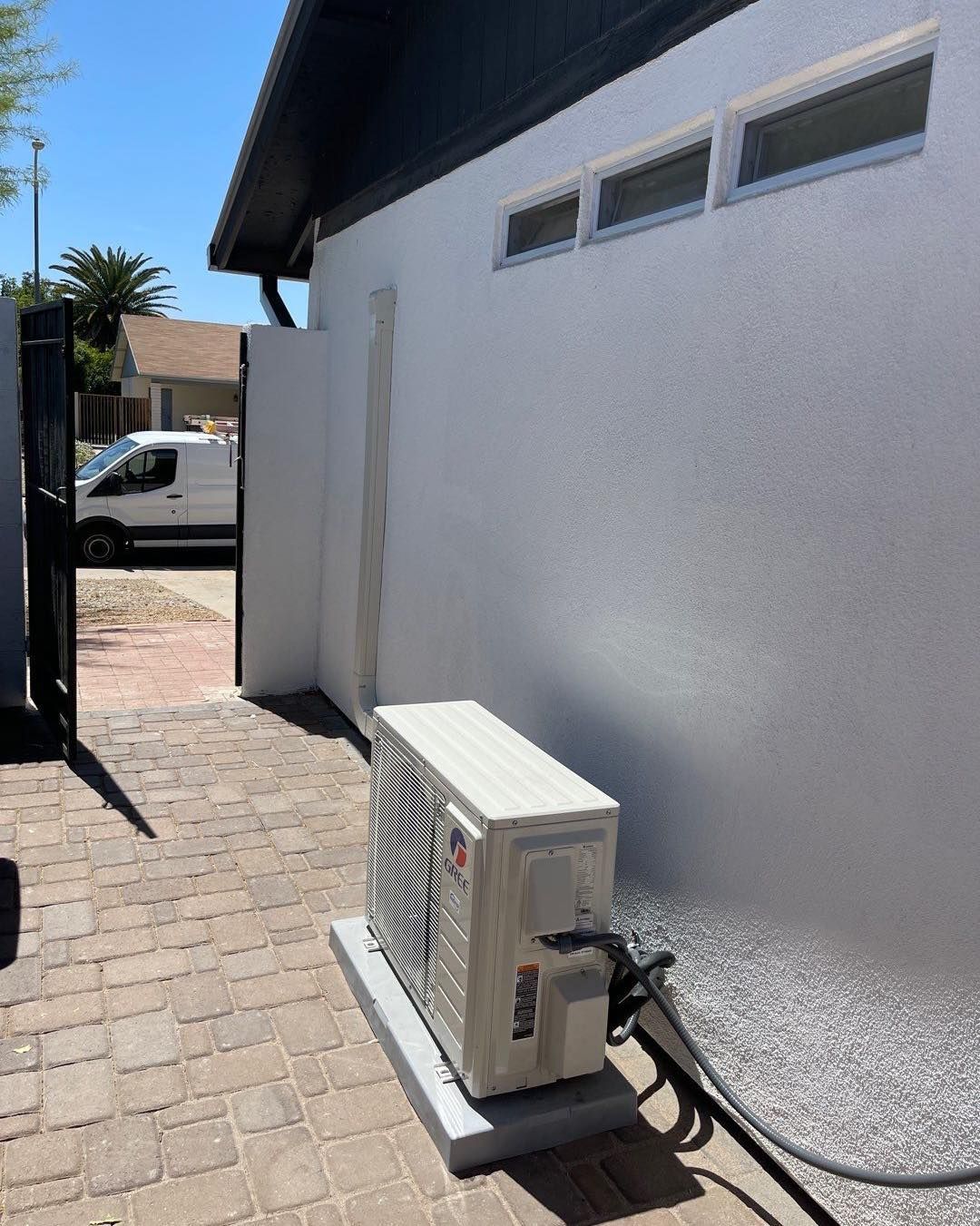 An air conditioner is sitting outside of a white building