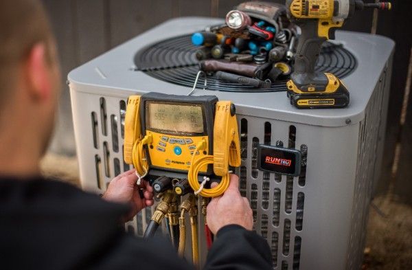 A man is working on an air conditioner with a drill.
