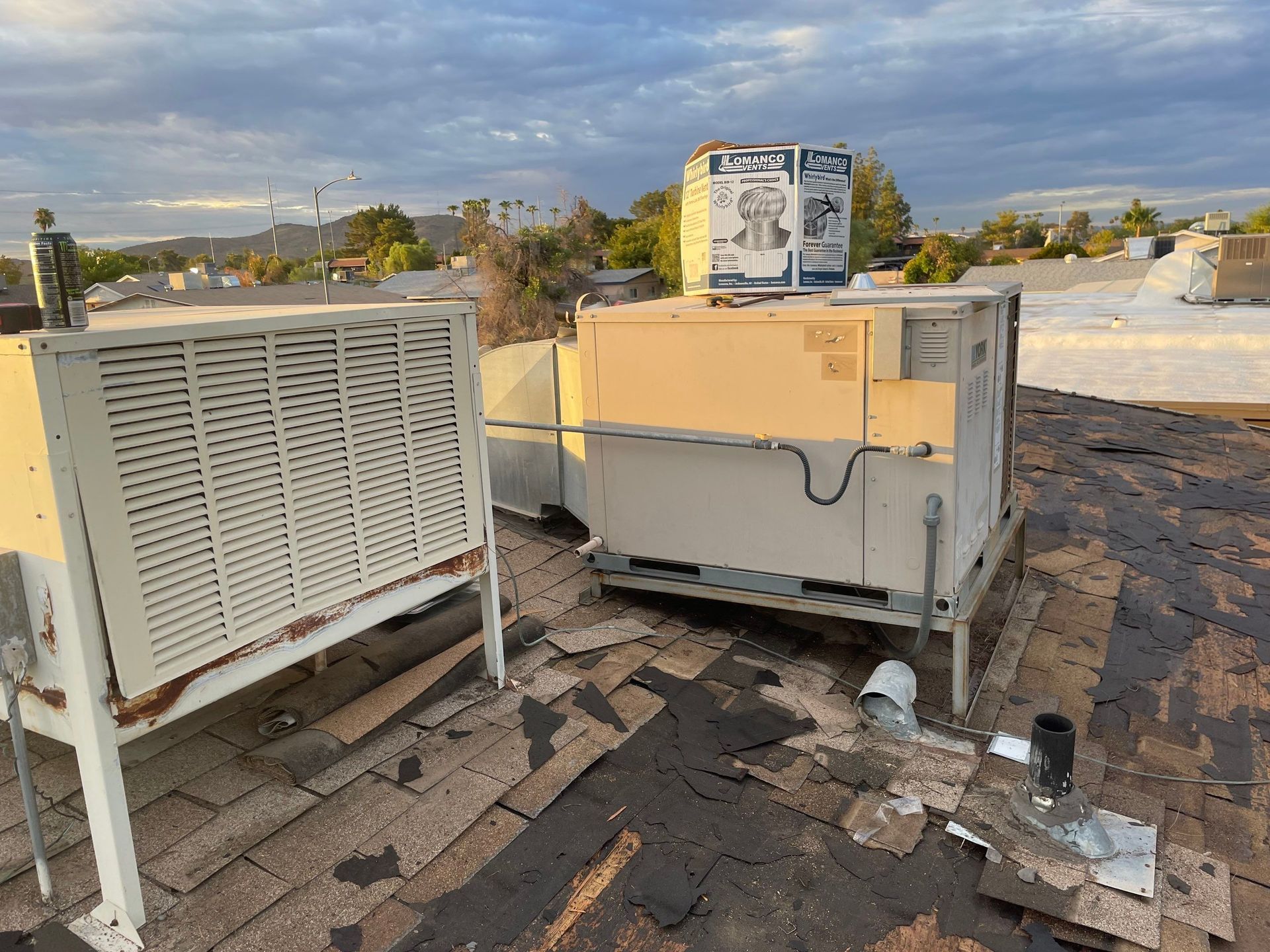 Two air conditioners are sitting on top of a roof.