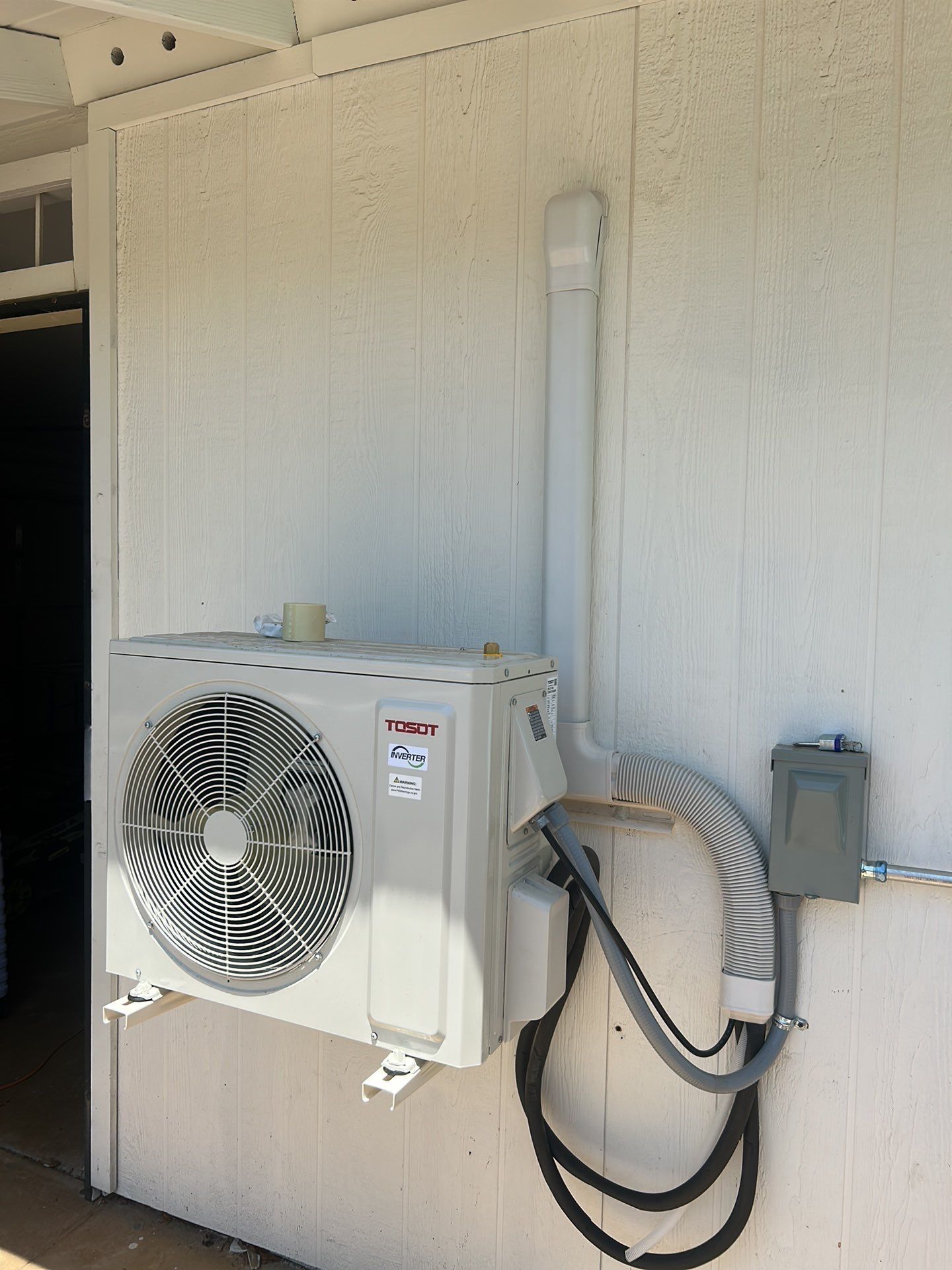 A white air conditioner is mounted on the side of a building.