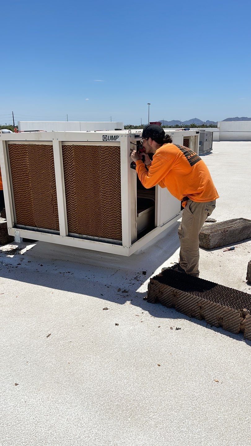 A man is working on an air conditioner on a roof.