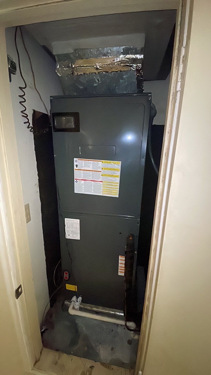 A large air conditioner is sitting in a closet next to a door.