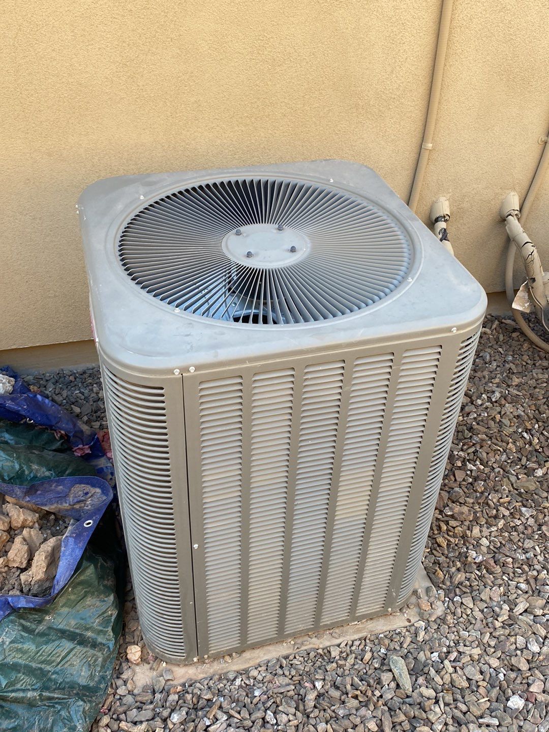 A large air conditioner is sitting on top of a pile of gravel.