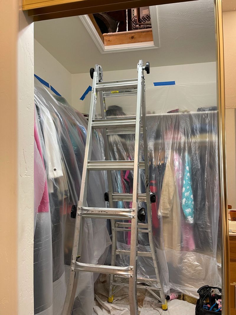 A ladder is sitting in a closet covered in plastic.