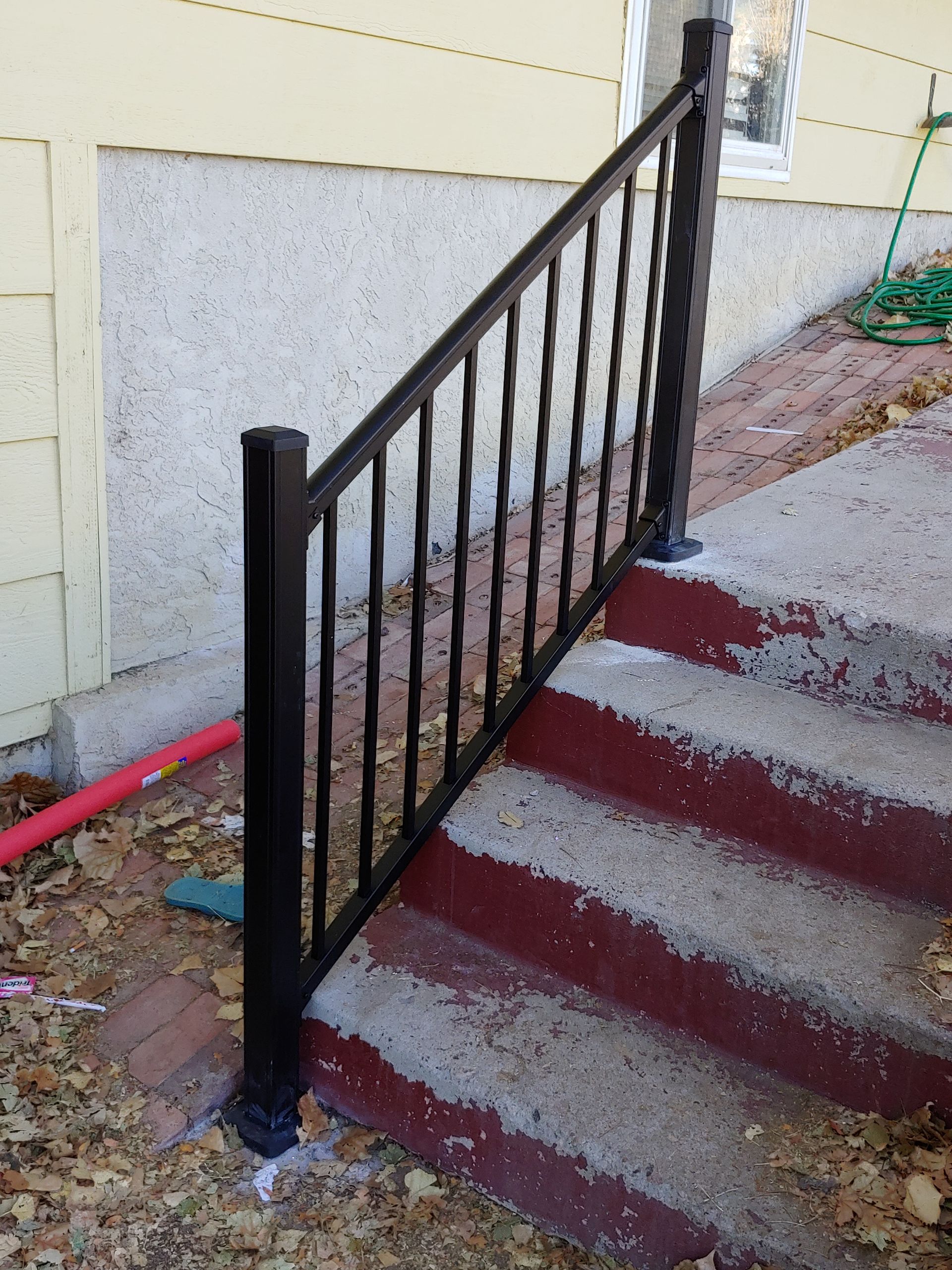 Black metal railing on concrete steps leading to a building.